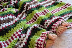 a baby's feet are tucked into a crocheted blanket