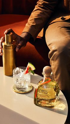 a man sitting at a table with two bottles of alcohol and a shaker on it