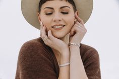 a woman wearing a hat and holding her hands to her face while posing for the camera