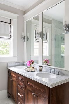 a bathroom with double sinks and large mirrors