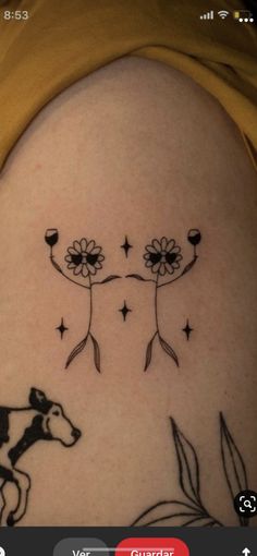 a woman's thigh with two flowers and a cow on it, in the middle of her leg