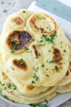 several flat breads are stacked on top of each other with parsley sprinkled on them