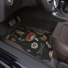 the interior of a car with flowers and dragonflys on black floor mats in front of it