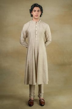 Sand grey full sleeves flared kurta in linen silk base with golden button detailing on placket and band collar neckline. Paired with matching churidar.
Components: 2
Pattern: Plain
Neckline: Band
Sleeve Type: Long
Fabric: Linen Silk
Color: Grey
Other Details: 
Closure: 
Kurta: Front placket buttons
Occasion: Groom - Aza Fashions Men Anarkali Kurta, Jatin Malik, Grey Anarkali, Silk Anarkali, Dhoti Pants, Anarkali Kurta, Haldi Ceremony, Royal Look, Indian Man