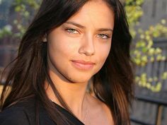 a close up of a person wearing a black shirt and long brown hair with blue eyes