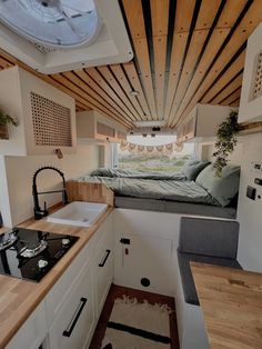 a tiny kitchen with sink, stove and bed in the back ground area that is made out of wood