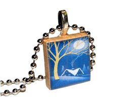 a small square pendant with a tree in the background and a house on it's side