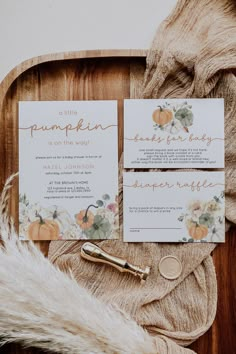 the wedding stationery is laid out on a wooden tray with fur and pumpkins