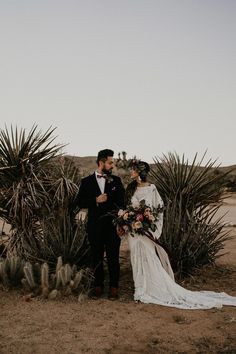 a bride and groom standing in front of cacti