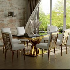 a dining room table with white chairs and a glass top in front of a brick wall