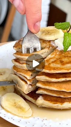 a pancake being cut with a knife and fork on a white plate topped with bananas