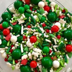 a bowl filled with green, red and white candies on top of a table