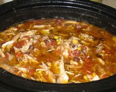 a crock pot filled with chicken, corn and tomato soup on top of a stove