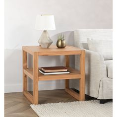 a small wooden table with a lamp on it next to a white couch and rug