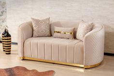 a beige couch with gold trim and pillows