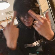 a man wearing a black hoodie making the peace sign