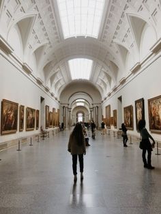 people are walking through an art museum with many paintings on the walls and ceilings,