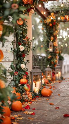 an outdoor area with pumpkins and greenery on the ground, lit by candles