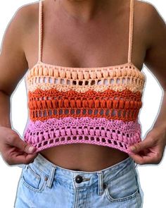 a woman is wearing a crochet top and denim shorts with her hands in her pockets