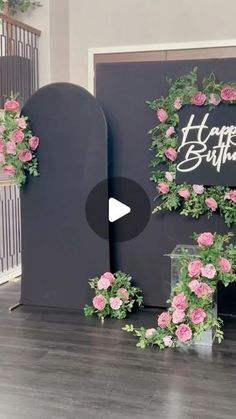 a happy birthday sign with pink flowers and greenery on the front entrance to a building