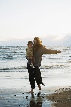 a woman holding a child on the beach