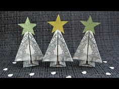 three origami christmas trees made out of dollar bills with gold and silver stars