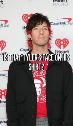 a man with red hair and black jacket standing in front of a white background that says, is that tyler's face on his shirt?