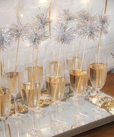 champagne flutes are lined up on a tray with snowflakes and sparklers in them