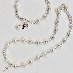 "This lovely Swarovski pearl and crystal bracelet is sure to be the perfect gift. -Bracelet measures 5 ½ inches plus a 1 inch extension chain. -The bracelet includes a pearl & crystal dangle and a cross. This bracelet has been a big seller for First Communion, Confirmation, Easter, Flower Girls, Maid-of-Honor, Bridesmaids, Mother-of-the-Bride, Godmothers, and Brides. Please see other listing for adult size. Necklace is a perfect match. -Necklace measures 13 ¾\" and has a 1\" extension chain. Pearl Charm Jewelry For First Communion, Adjustable Pearl Jewelry For Gifts, Adjustable Pearl White Necklace As A Gift, Elegant Pearl White Jewelry For First Communion, Elegant Adjustable Rosary Bracelet For Birthday, Pearl Jewelry For Birthday And Mother's Day, Adjustable Pearl Bracelet For First Communion, White Pearl Charm Jewelry For First Communion, Adjustable Pearl Jewelry For Birthdays