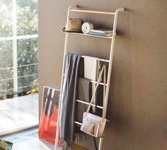 a white shelf holding purses and other items next to a wall with a window in the background