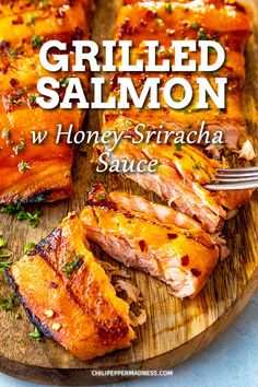 grilled salmon with honey - sriraca sauce on a wooden cutting board next to a fork