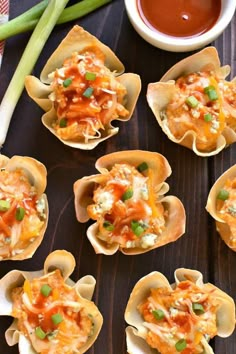 small cups filled with food sitting on top of a wooden table next to celery sticks