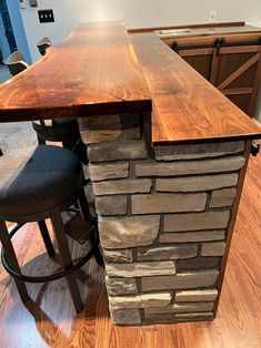 a kitchen island made out of wood and stone with two stools next to it