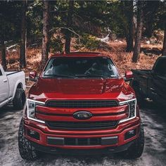 two trucks parked in the snow near trees