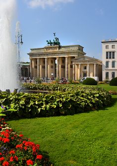 the building has columns and pillars on it's sides, along with flowers in the foreground