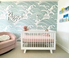 a baby's room with a crib, chair and wallpaper in the background