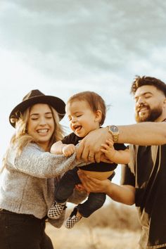 a man and woman holding a baby in their arms