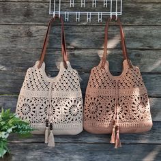 two crocheted purses hanging on a wooden wall next to a potted plant