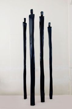 three black poles are standing in front of a white wall