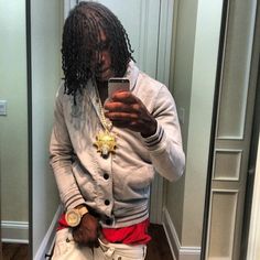 a man with dreadlocks is looking at his cell phone in front of a mirror