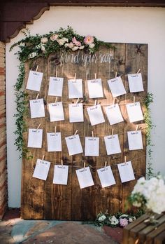 a wooden sign with notes attached to it and flowers on the wall next to it