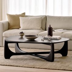 a living room with a couch, coffee table and pillows on the carpeted floor