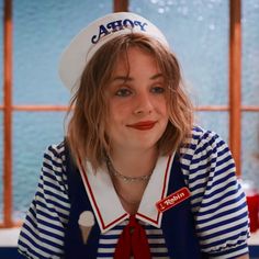 a woman wearing a sailor's hat and striped shirt is looking at the camera