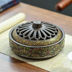 a decorative container sitting on top of a wooden table next to a cup and saucer