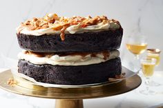 there is a chocolate cake with white frosting and walnuts on the top, sitting on a gold platter