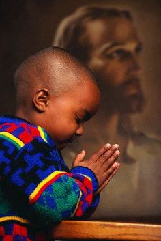 a small child is praying in front of a painting