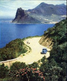 an old car parked on the side of a road next to a body of water