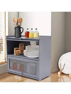 a microwave oven sitting on top of a wooden floor next to a table with plates and utensils