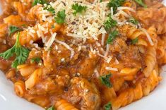 a white bowl filled with pasta covered in sauce and parmesan cheese on top