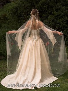 a woman in a wedding dress with a veil on her head and arms outstretched to the side